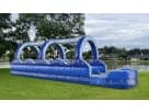 Blue 32ft double lane slip and slide rental set up in a Houston backyard, ideal for summer parties in Spring with kids and adults.