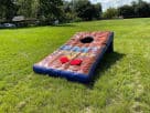 Perfect for Houston parties, this giant inflatable cornhole rental measures 5 feet wide by 8 feet long with red bean bags